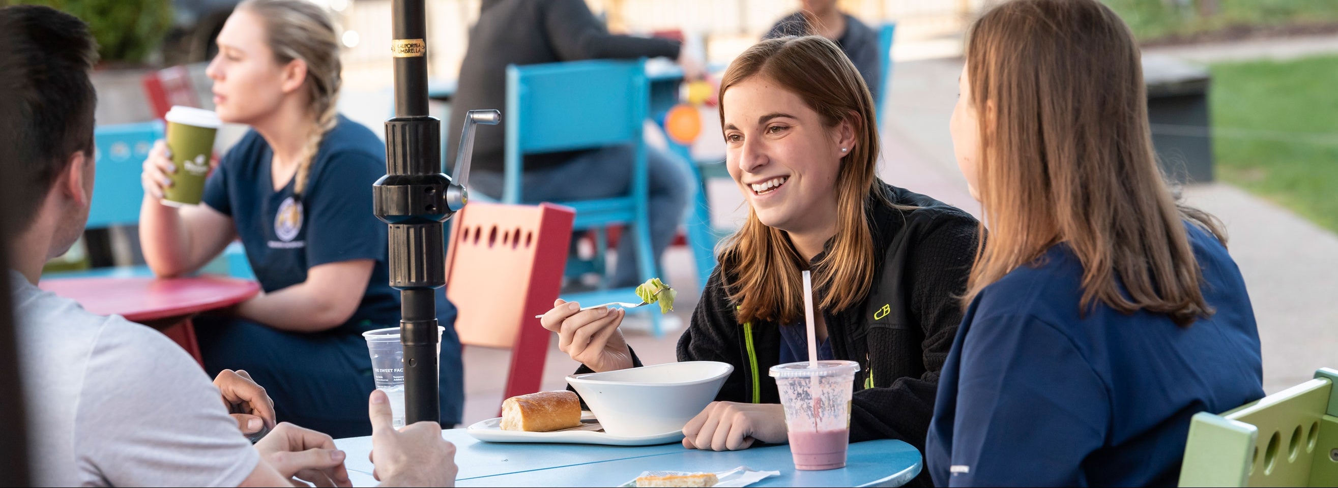 A woman eats a meal while dining outdoors with friends