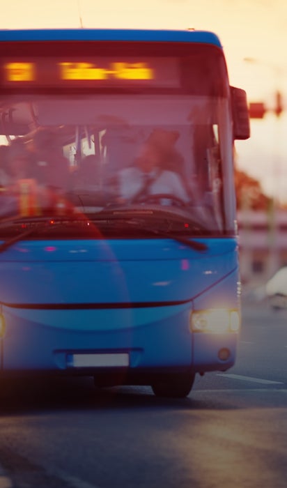 The front of a bus as it travels down a street