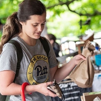 A student purchases items at the Pitt Farmers Market