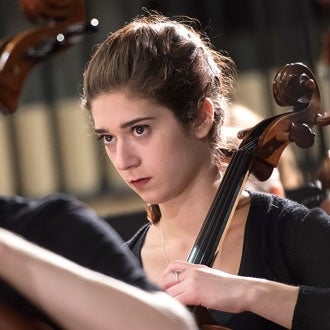 A musician plays a string instrument at the symphony