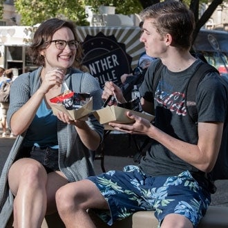 Two students eat lunch by the Panther Grille food truck